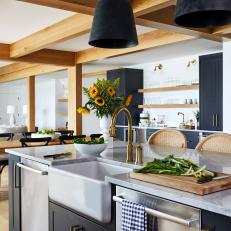 Bright Kitchen Features Exposed Beams, Modern Pendant Lights, a Marble Island and a Farmhouse Sink