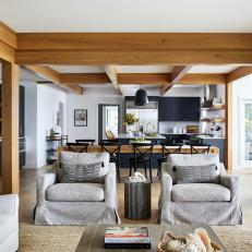 Open Living Space Features a Kitchen With Exposed Beams, a Large Dining Table and a Neutral Living Room