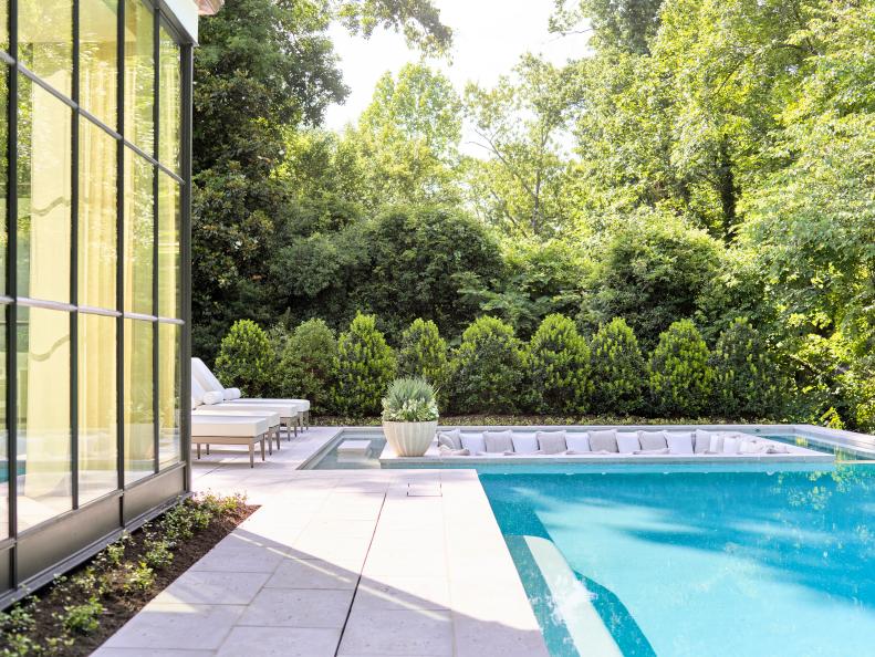 A modern backyard features a pool and a glass-walled family room.