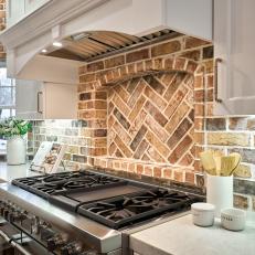Rustic Brick Backsplash Accents a Cottage-Style Kitchen That Features a Gas Range
