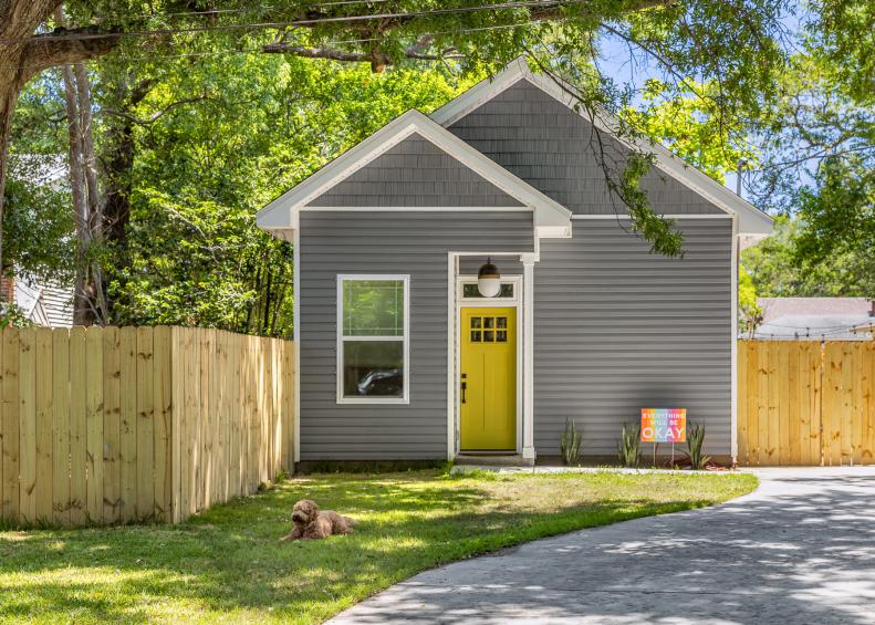 Fluffy Dog on Lawn Near Fence at Tiny Home With Bold Front Door