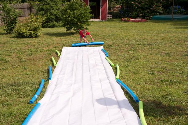 Lay out the pool noodles on either side of your DIY slip and slide.
