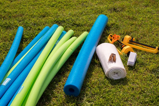 You'll need pool noodles, 6 mil plastic sheeting, some stakes, Velcro tape, scissors and sprinklers for your DIY slip and slide.
