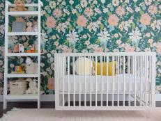 White Crib, Ladder Shelf, Plush Rug in Nursery With Floral Wallpaper