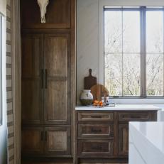 Wood Cabinetry Lines the Back of a Rustic Kitchen That Features a Large Marble-Topped Island