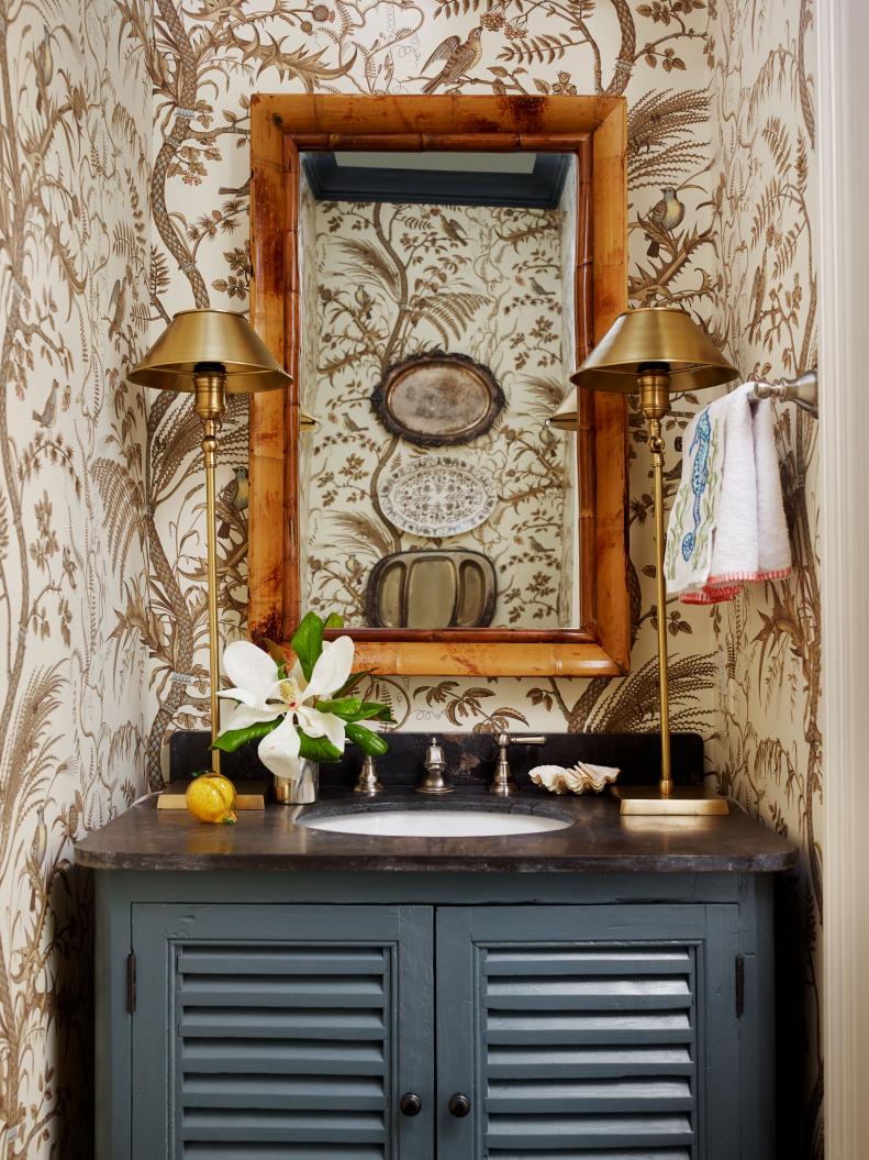 Powder room with dark vanity topped with two gold lamps.