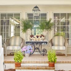 Traditional Coastal Porch with Striped Rattan Armchairs and Antique Table 