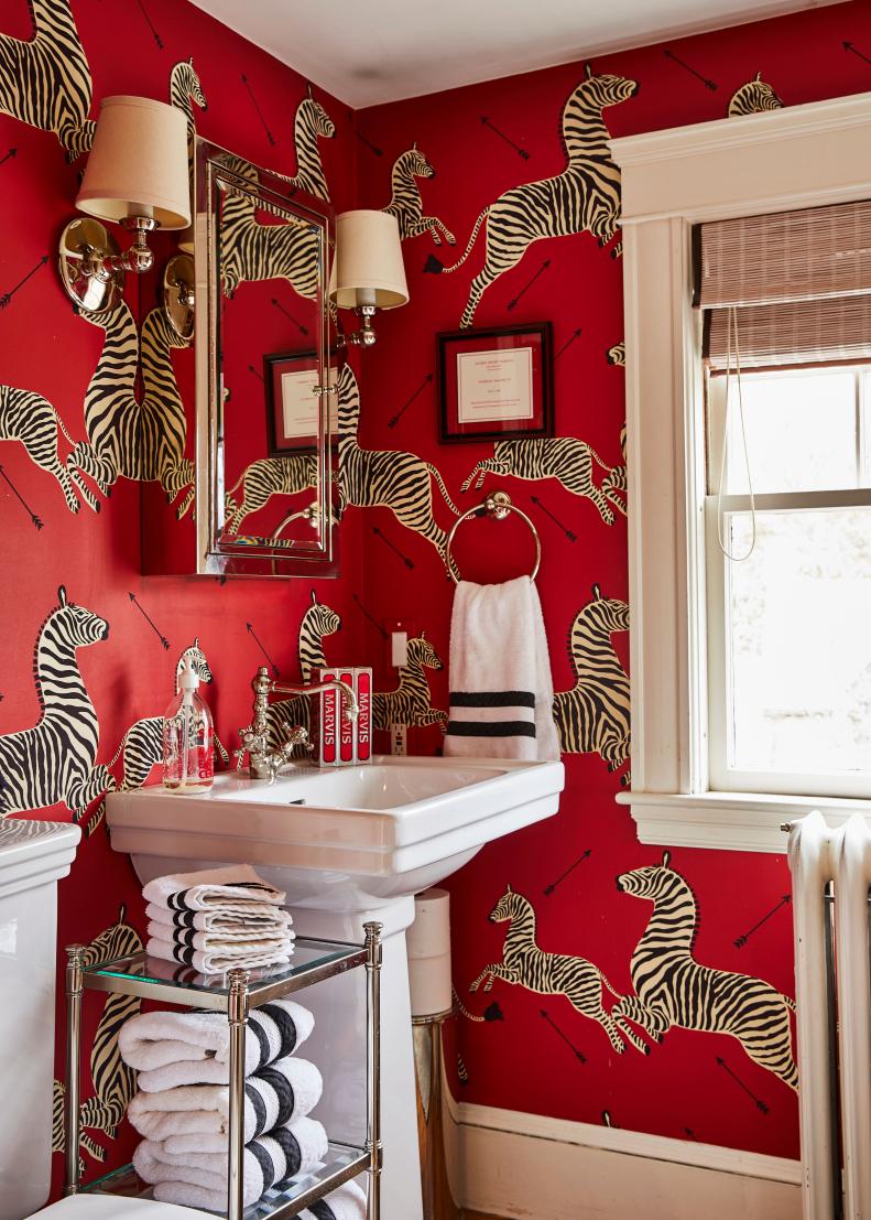 A bathroom has bold red zebra-print wallpaper and white fixtures.