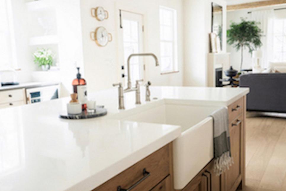 White Countertops With An Inset Farmhouse Sink Sit Atop Wood Cabinets Hgtv