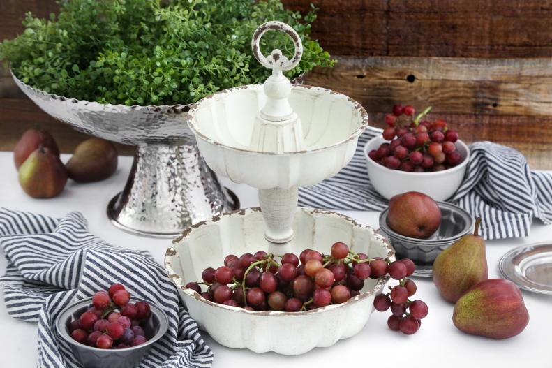 Nesting Bundt pans can be fashioned into a handy tiered server (or organizer!) with wooden dowels or spindles. Drill a hole in both ends of a long dowel and add an interior dowel screw to each end. Secure the dowel to the opening in the center of the large bottom loaf pan with a washer and wingnut. Stack the smaller loaf pan on the top of the dowel so that the end of the screw comes through the hole in the center of the pan. Finish the top with a with a decorative screw-on finial. Chalk paint can be used to add color and distress the finish to match your décor.