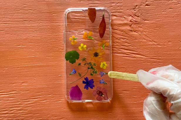Use a wood craft stick to lightly spread the resin over the flowers. Ensure that each flower is completely covered with resin so the surface dries evenly and smoothly.