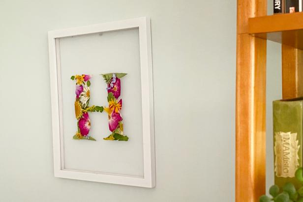 Float Frame on Wall Filled With Pressed Flowers That Form an H