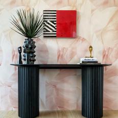Modern Black Table Featuring Decorative Accents Sits Against a Wallpapered Wall 