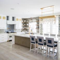 Eclectic Kitchen Features White Cabinets With Gold Hardware and a Large Marble-Topped Island