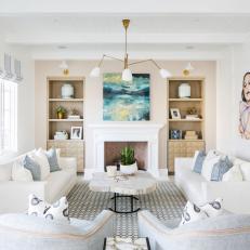 Neutral Living Room Features Built-In Bookshelves, a White Fireplace and Matching Sofas