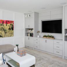 Neutral Living Room Features a Built-In Entertainment Center and a Multicolor Piece of Art