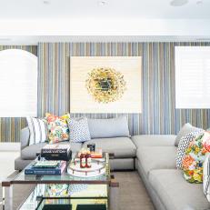 Eclectic Living Room Features Striped Wallpaper, a Gray Sectional and a Brass and Glass Coffee Table