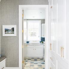 Neutral Mudroom Features Built-In Cabinets With Gold Hardware and a Hexagon Tile Floor