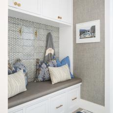Neutral Mudroom With Grasscloth Wallpaper Features a Built-In Storage Bench Topped With Multicolor Throw Pillows 