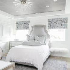 Bright Bedroom Features an Upholstered Headboard, Patterned Roman Shades and a Unique Light Fixture