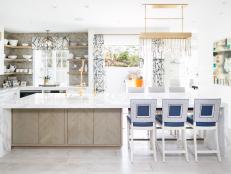 Bright Kitchen Features a Large Marble-Topped Island, a Glass Tile Backsplash and a Modern Gold Chandelier