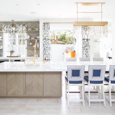 Bright Kitchen Features a Large Marble-Topped Island, a Glass Tile Backsplash and a Modern Gold Chandelier