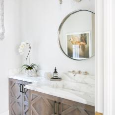 Small Powder Room Features a Single Wood Vanity With a Marble Countertop and a Round Mirror 
