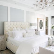 Bright Bedroom With a Wallpaper Accent Wall Features an Upholstered Headboard and a Matching Bench