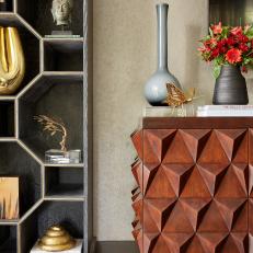 Walnut Credenza Sits Next to a Geometric Bookshelf Filled With Gold Accents