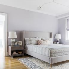 Neutral Bedroom Features an Upholstered Bed and a Modern Light Fixture