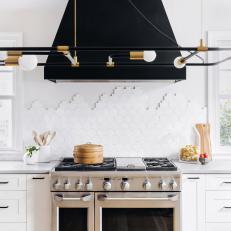 Bright White Kitchen Features a Black Range Hood and a Geometric Tile Backsplash
