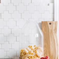 White Mosaic Tile Backsplash, Laid in an Unusual Pattern, Is Featured in an All-White Kitchen