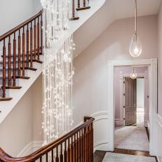 A Double Staircase Features Walnut Banisters and a Glamorous Chandelier