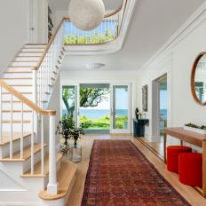 Bright Foyer Features a Large Staircase, Globe Hanging Lights and a Vintage Runner