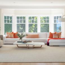 Bright Living Room With Bay Windows Features an Upholstered Sectional, Modern Armchairs and a Midcentury Modern Coffee Table and a Gold Floor Lamp 