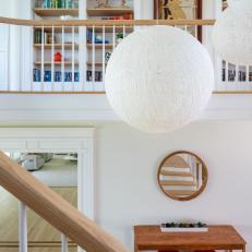 A Bright Landing Features Built-In Bookshelves,  Eclectic Hanging Globe Lights and a Traditional Railing