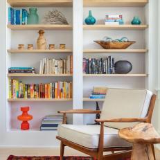 Bright Sitting Area Features Built-In Bookshelves Filled With Colorful Books and an Upholstered Armchair 