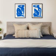 Bedroom Features Modern Art Hanging Above an Upholstered Headboard and Matching White Nightstands