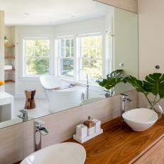 Bright Bathroom Features a Floating Double Vanity, a Freestanding Tub and Bay Windows