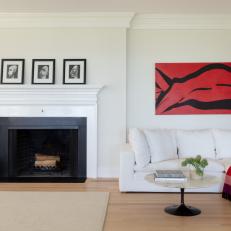 Bright Living Room Features a Traditional Fireplace, a White Sectional and a Bold Piece of Art