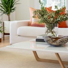 Bright Living Room Features a Midcentury Modern Coffee Table and a White Sofa Topped With Multicolored Pillows