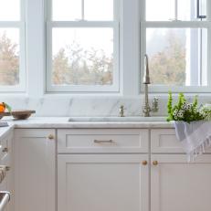 Graceful White Countertop and Cabinetry Punctuated by Brass