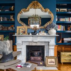 Midcentury Modern Living Room Features Dark Blue Walls, a Marble Fireplace and Built-In Bookshelves