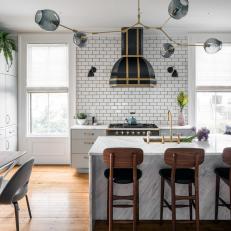 Modern Kitchen Features a Subway Tile Backsplash, a Marble Island and a Black Range Hood