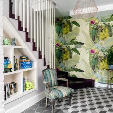 An Antique Chair Sits at the Base of a Modern Staircase in Front of a Wallpaper Accent Wall