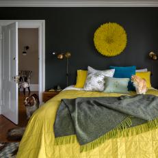 Moody Bedroom Features Wall-Mounted Light Fixtures and a Large Bed Topped With a Variety of Throw Pillows