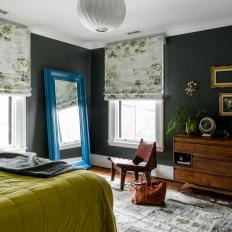 Moody Bedroom Features a Large Blue Mirror, Traditional Roman Shades and a Modern Light Fixture 