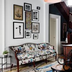 Bright Foyer Features a Black Accent Ceiling, a Black and White Gallery Wall and a Patterned Sofa