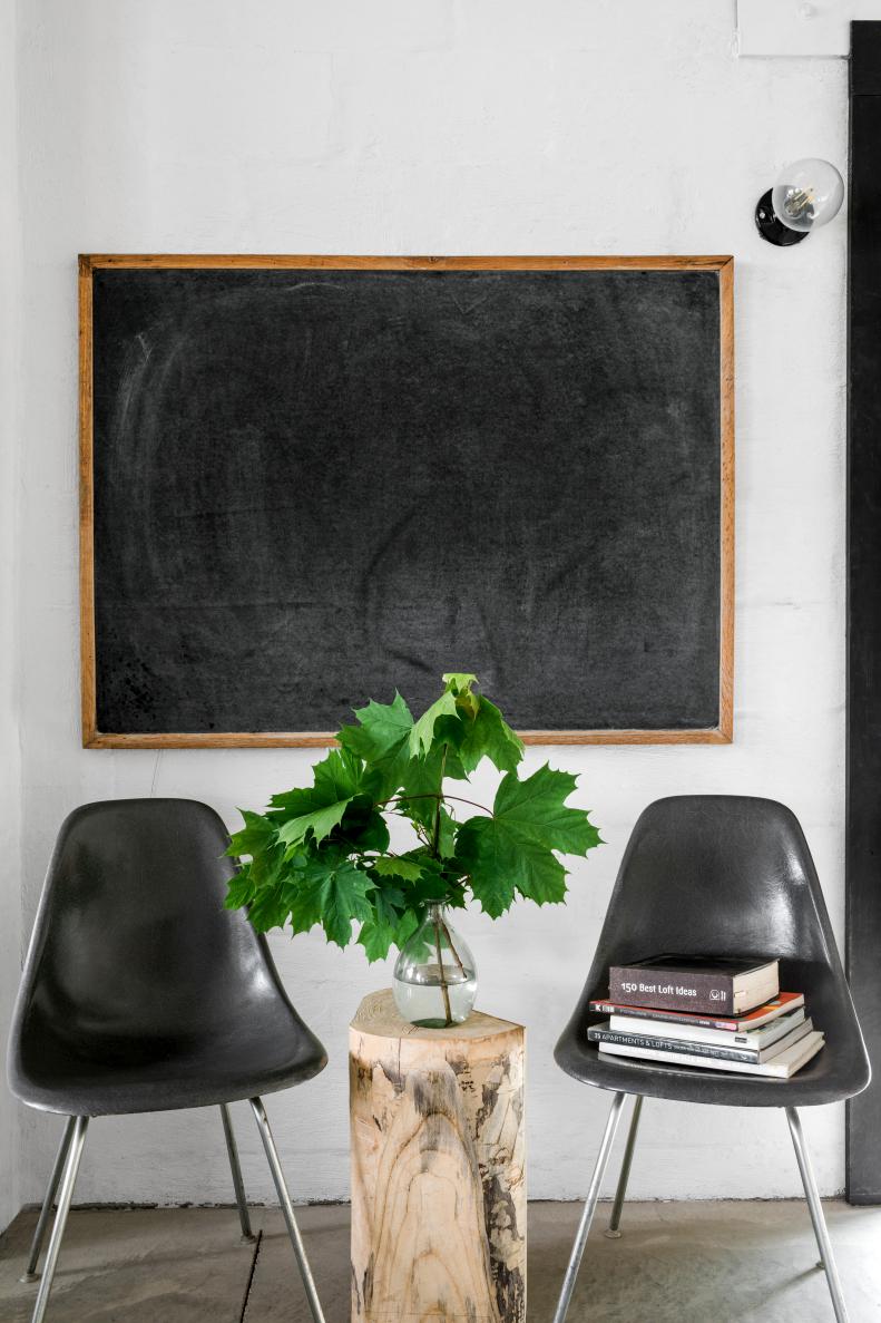 An ongoing design element seen throughout Steve Ford's garage is vintage schoolhouse style. The molded fiberglass chairs are from 1960s grade schools along with a 1970s era chalkboard. All of the cinderblock and brick walls are painted white, a staple feature of homes designed by sister Leanne Ford. 