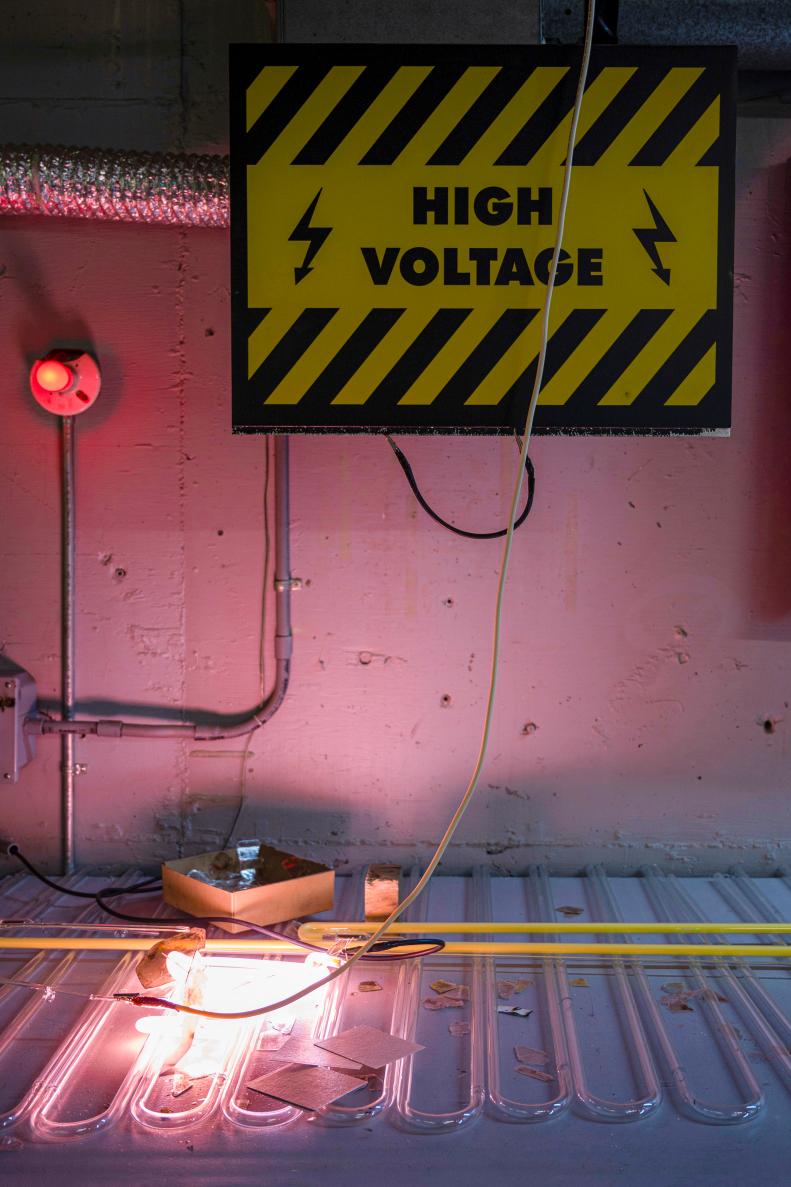 High Voltage Sign and Red Light at Work Station With Bright Neon Sign